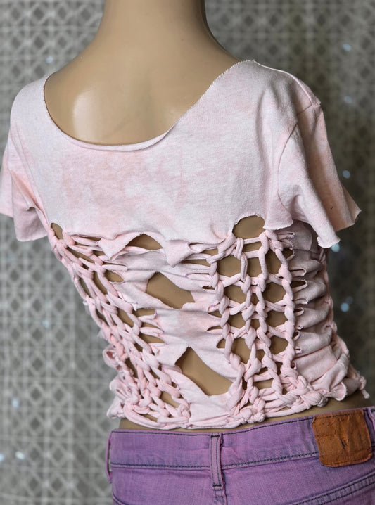 Pink lace-up top on a mannequin against a textured wall background