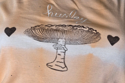 Peach tank top with black mushroom design on a textured surface