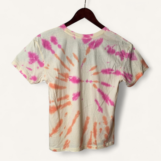 Tie-dye t-shirt with pink and orange patterns on a hanger against a white background