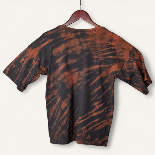 Tie-dye t-shirt with bleach dyed pattern on a hanger against a white background