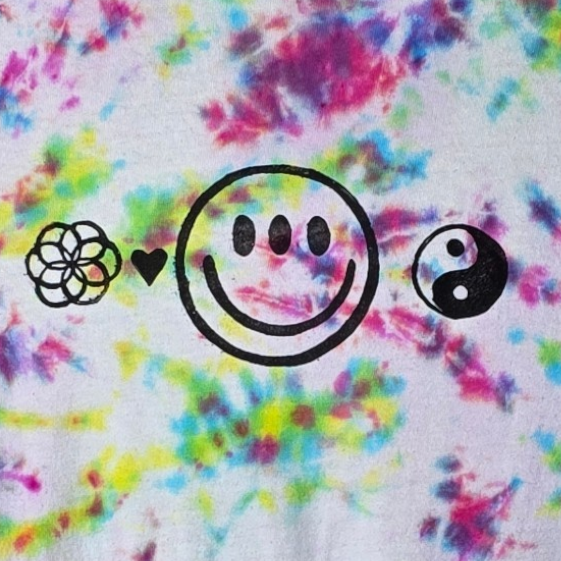 Colorful tie-dye t-shirt with smiley face design on a hanger against a white background