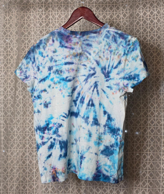 Tie-dye t-shirt on a hanger against a patterned wall