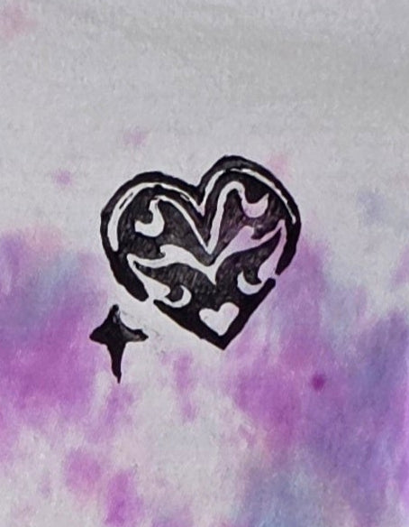 Tie-dye t-shirt with a heart design on a hanger against a patterned wall.