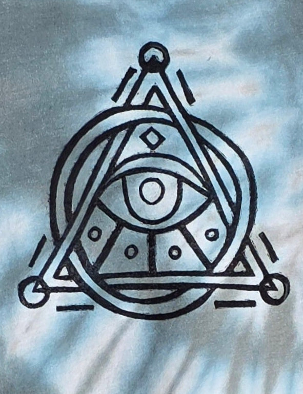Tie-dye t-shirt with a symbol on a hanger against a patterned wall.