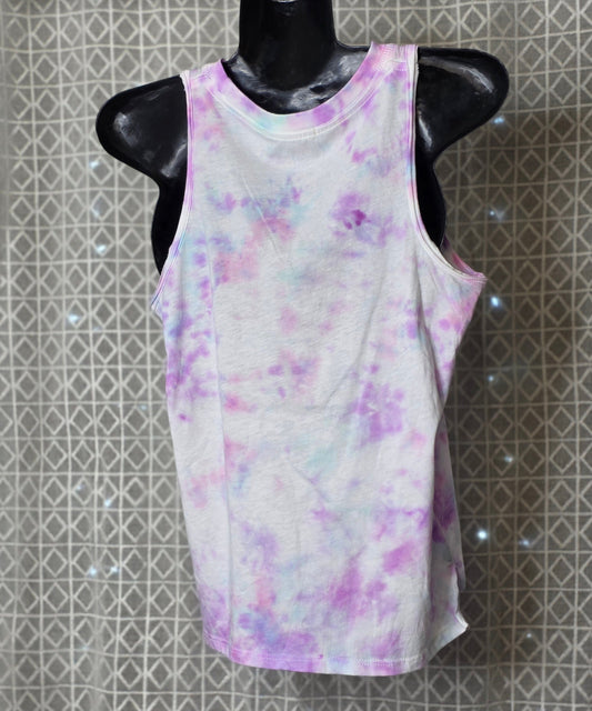 White tank top with purple and pink watercolor design on a mannequin against a patterned wall.