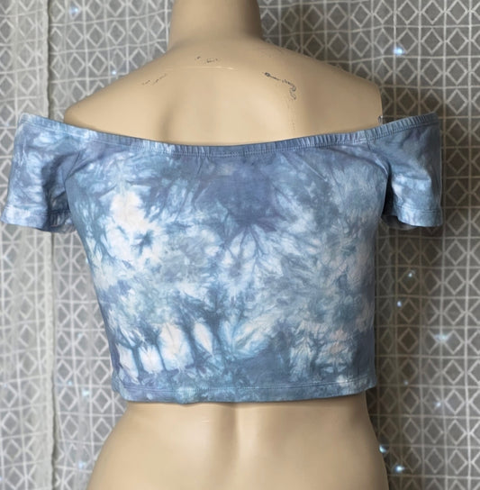 Blue tie-dye off-shoulder top on a mannequin against a patterned wall.