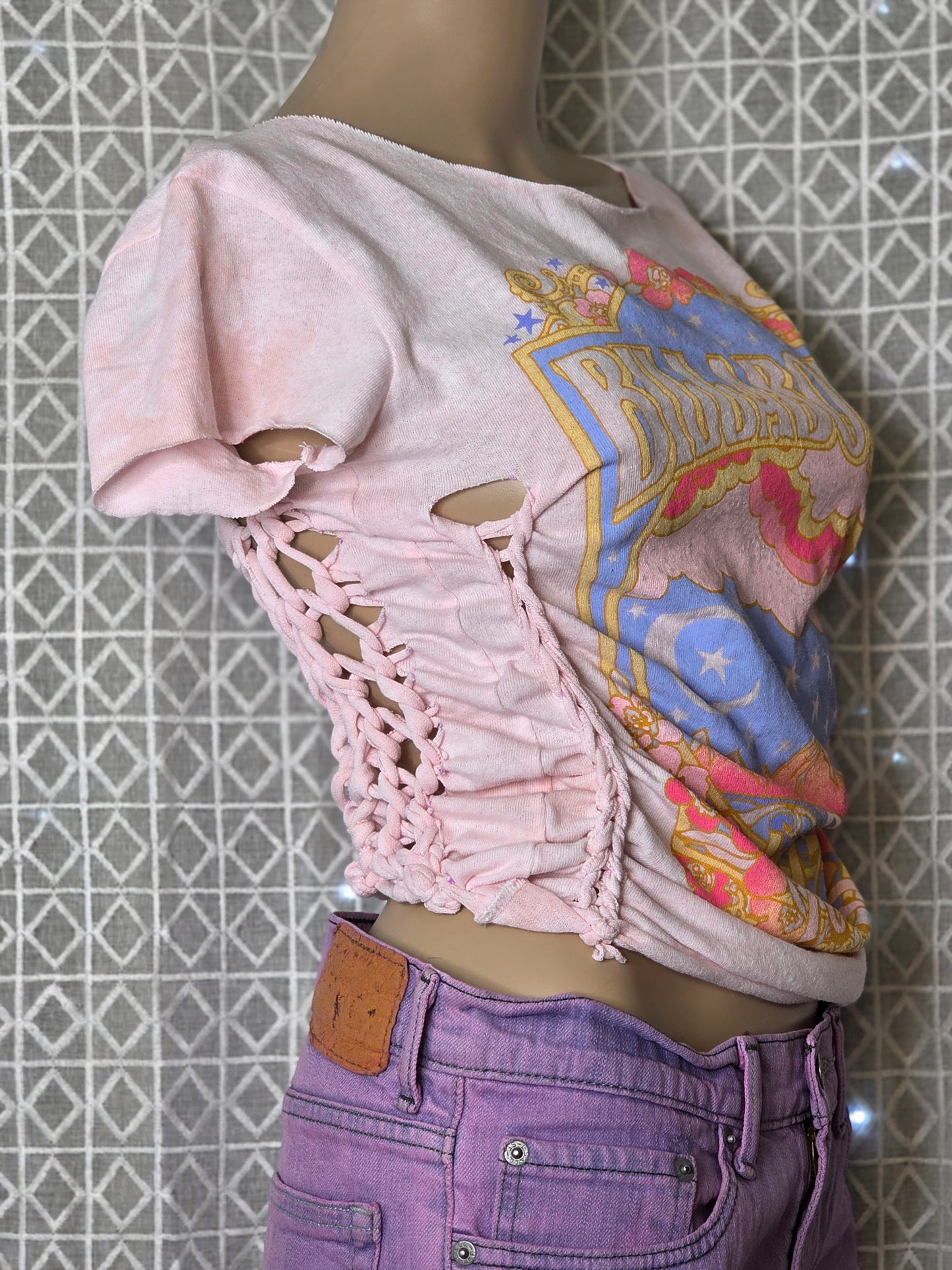 Close-up of a person wearing a patterned top, lace shorts, and purple pants on a tiled floor.