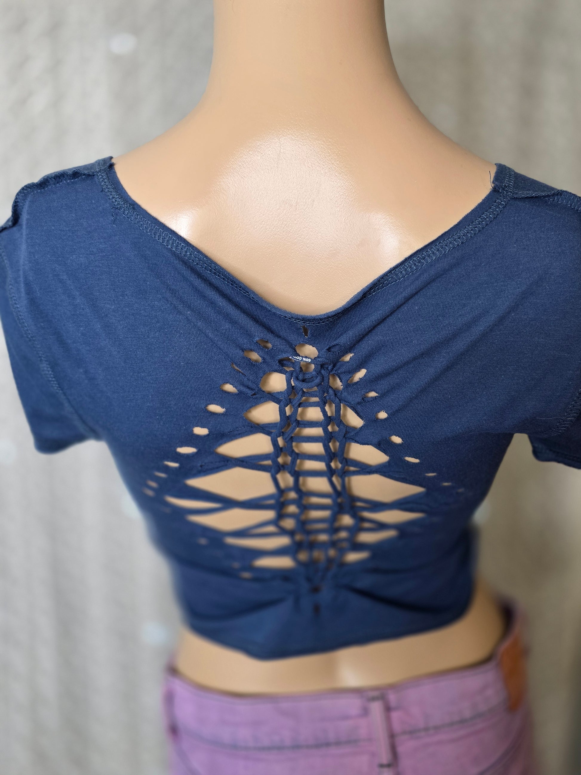 Navy blue top with cut-out design on a mannequin against a neutral background