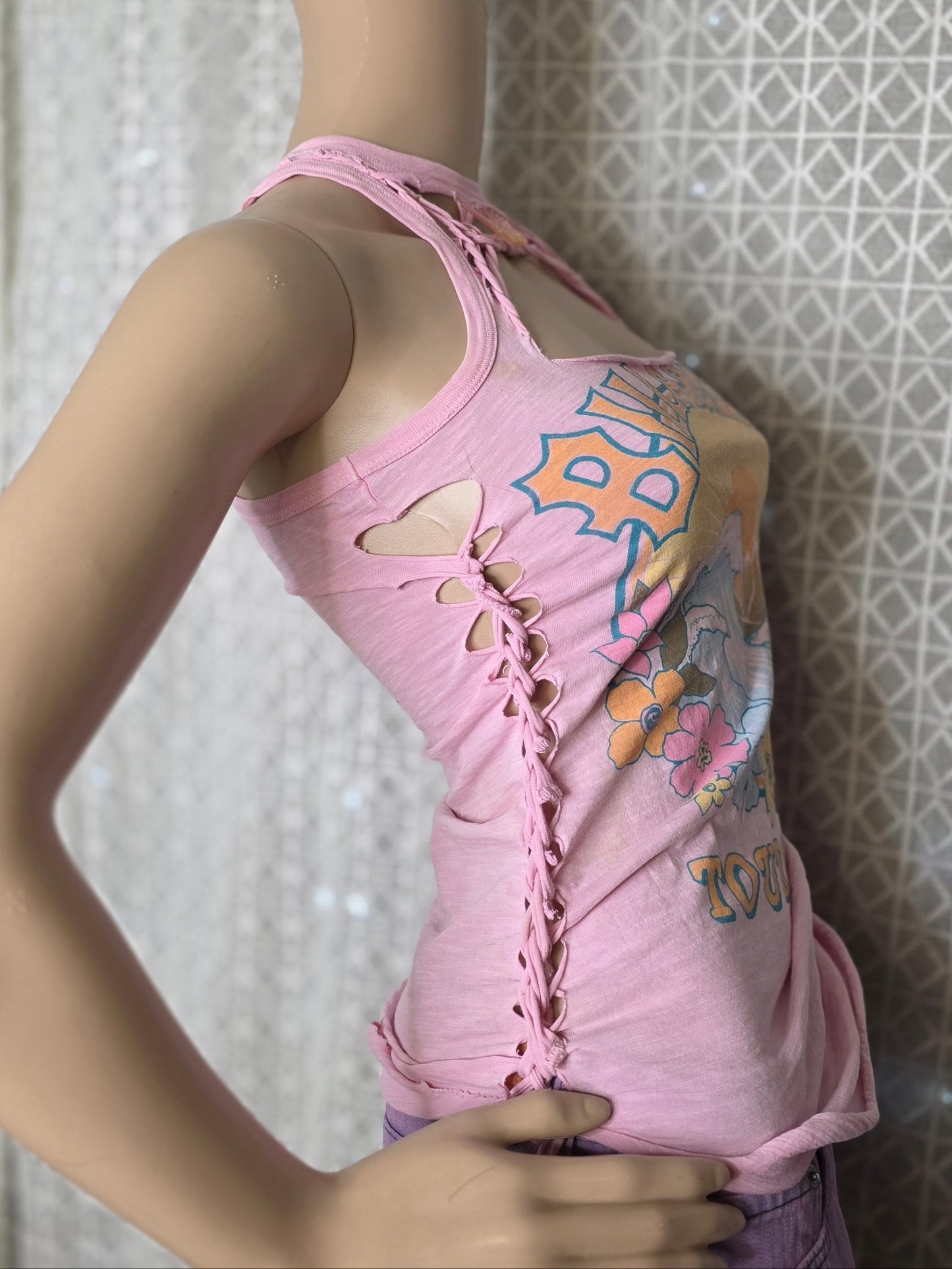 Pink sleeveless top with colorful designs on a textured wall background