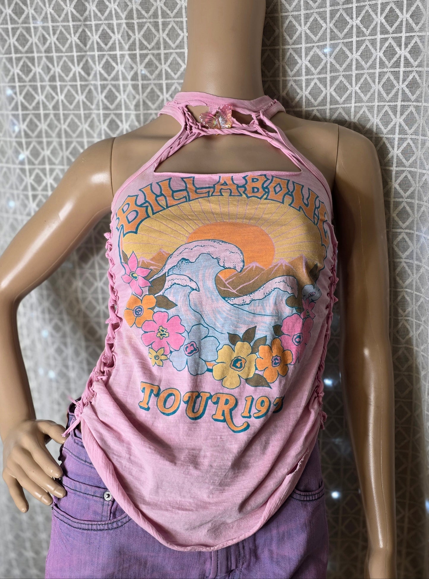 Mannequin wearing a pink tank top with a graphic design against a patterned wall.