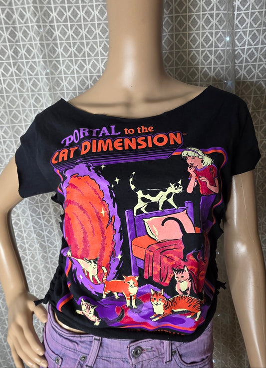 Mannequin wearing a black t-shirt with colorful graphic design against a patterned wall.