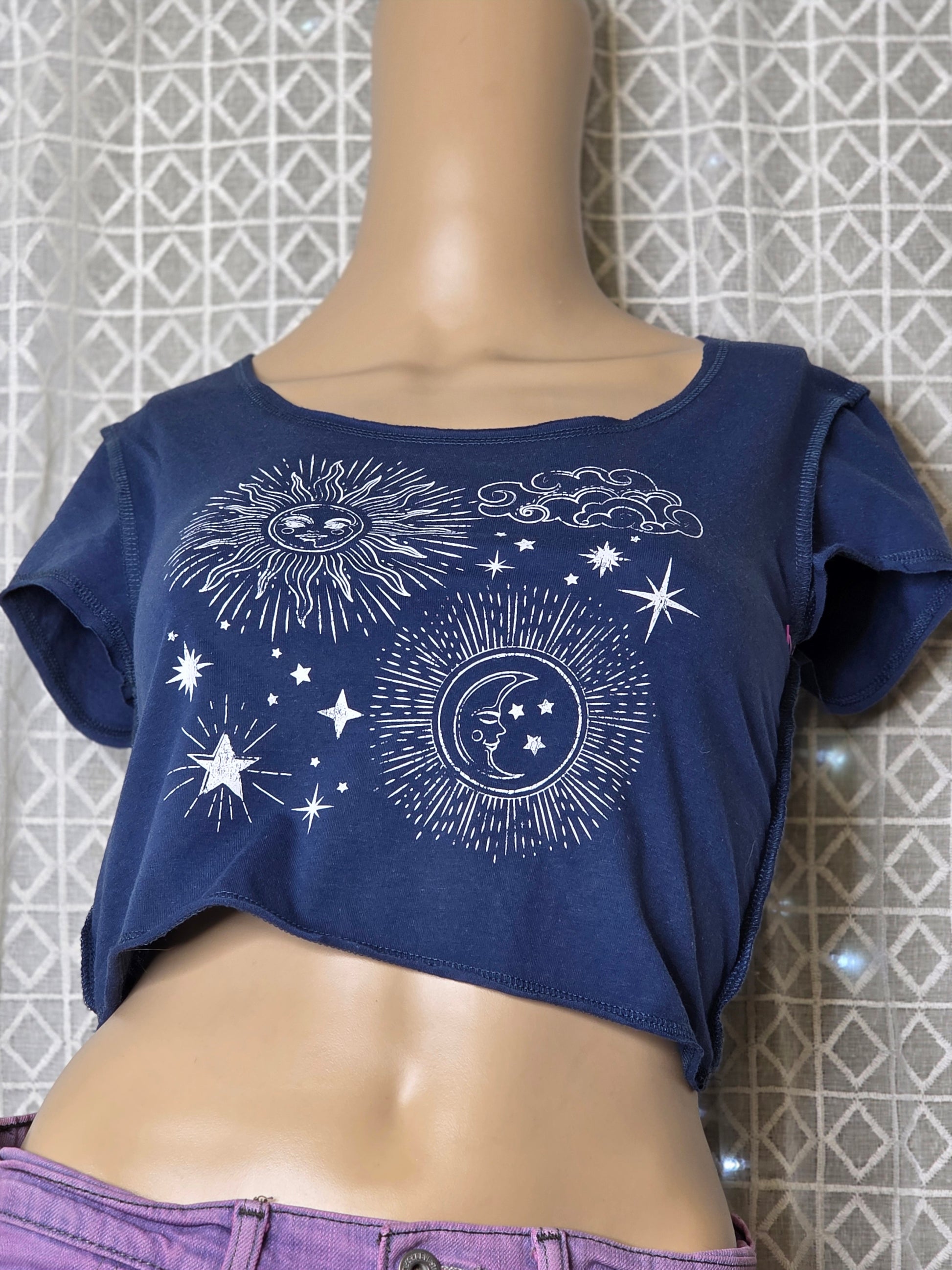 Navy blue garment with celestial design on a mannequin against a tiled wall.