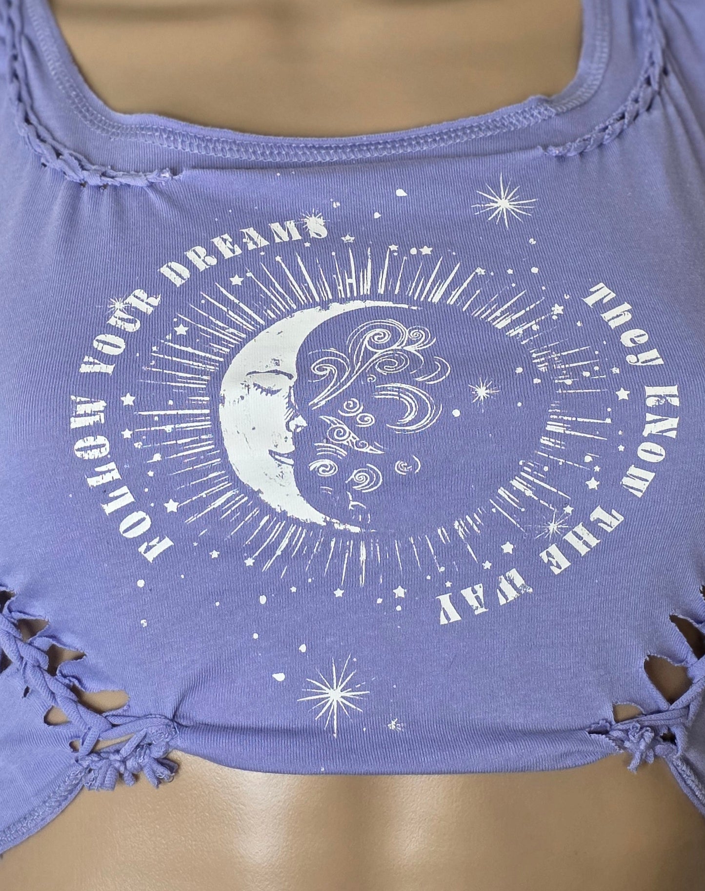Purple crop top with celestial design on a mannequin against a patterned wall.