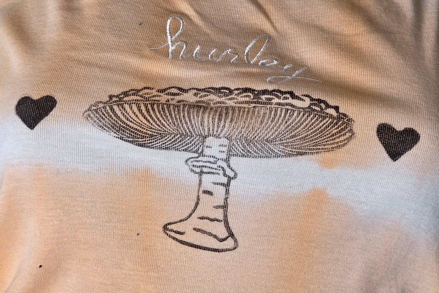 Peach tank top with black mushroom design on a textured surface