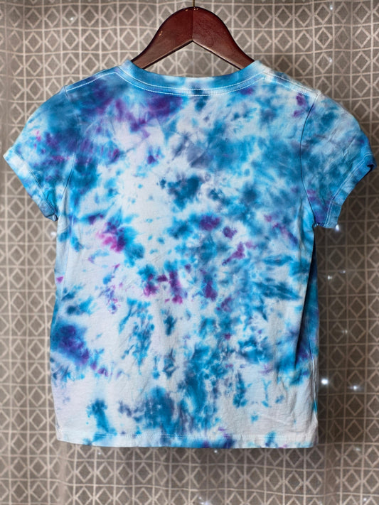Tie-dye t-shirt on a hanger with a pattern of blue, purple, and white.