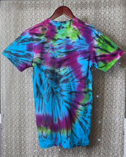 Tie-dye t-shirt on a hanger against a patterned wall
