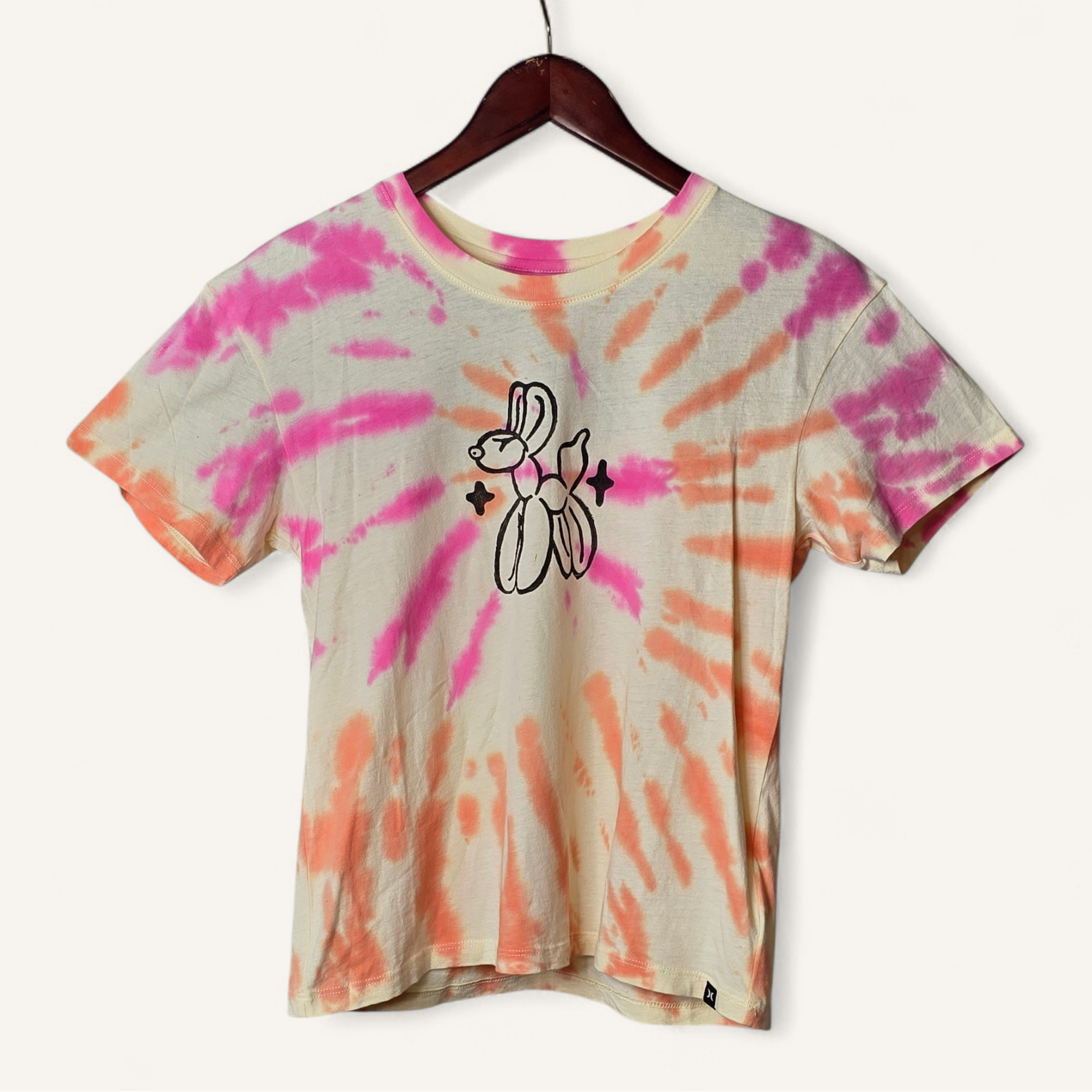 Tie-dye t-shirt with a graphic design on a hanger against a white background