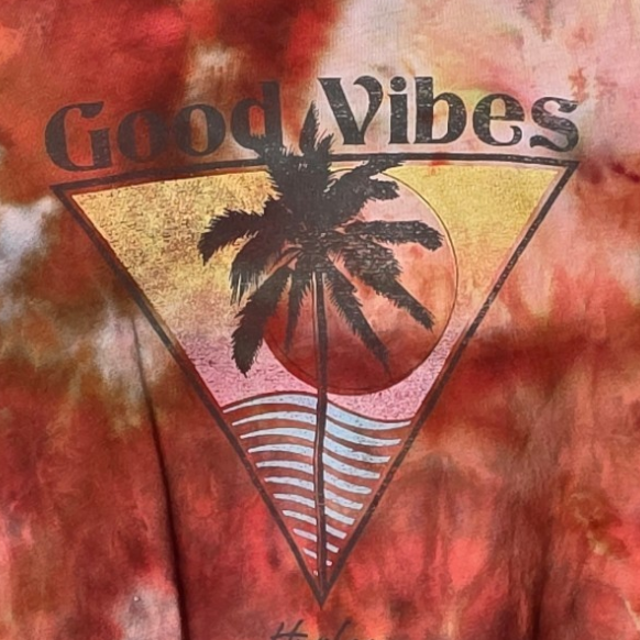 Tie-dye t-shirt with 'Good Vibes' graphic on a hanger against a white background