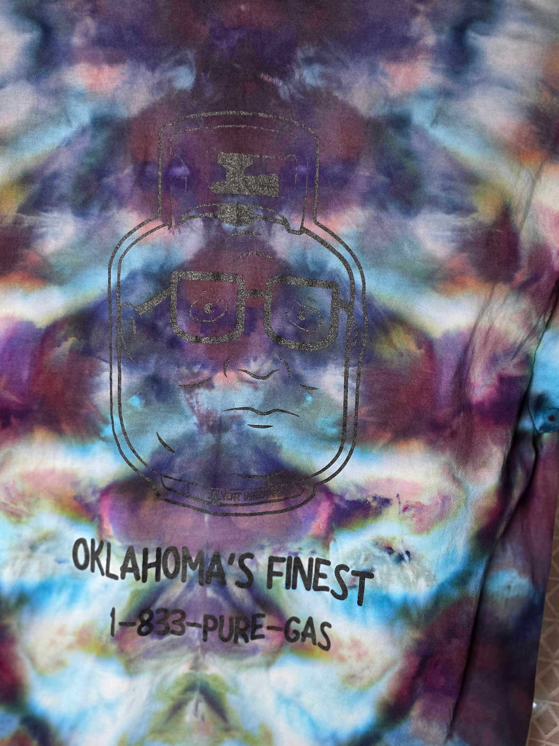 Colorful tie-dye pattern with 'Oklahoma's Finest' branding on a textured surface.