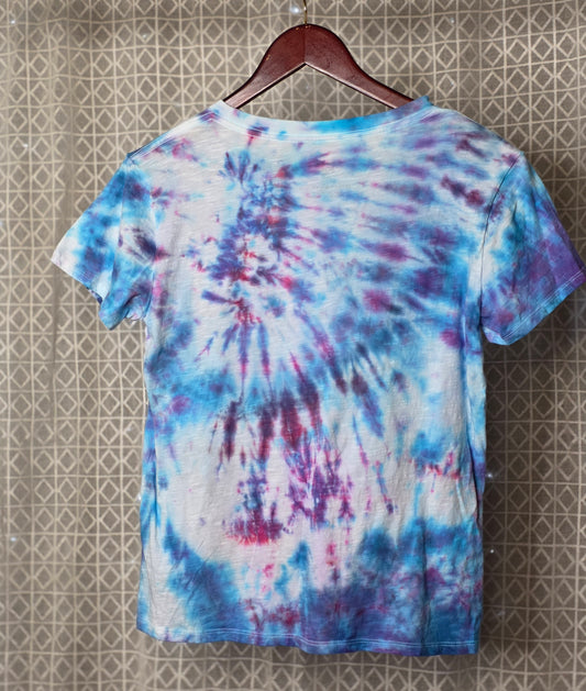 Tie-dye t-shirt on a hanger against a patterned wall
