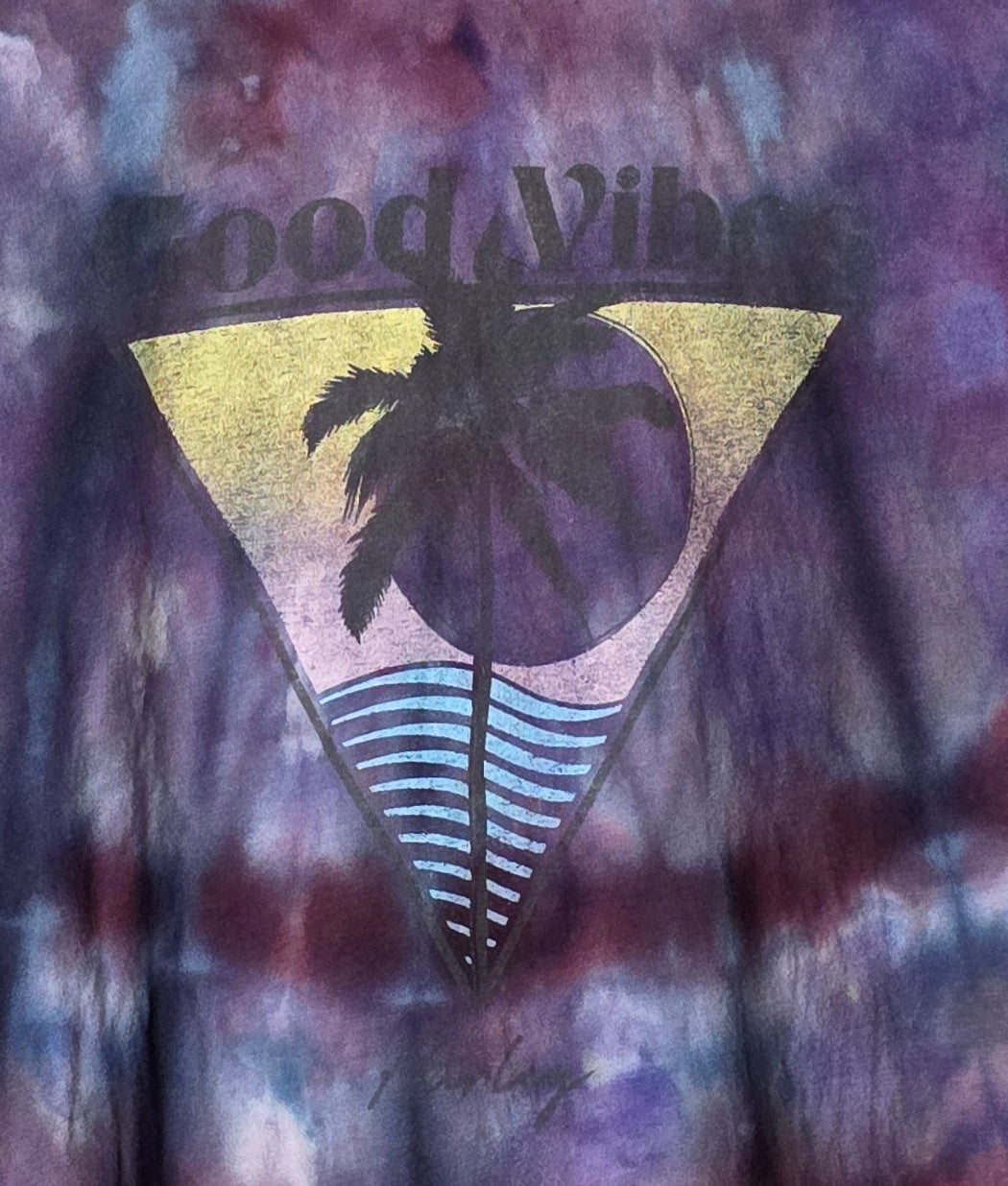 Tie-dye shirt with 'Good Vibes' design featuring a palm tree and striped pattern on a multicolored background.