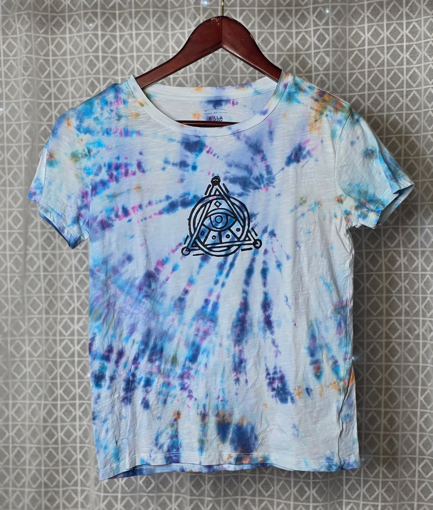 Tie-dye t-shirt with a black triangle on a textured wall background