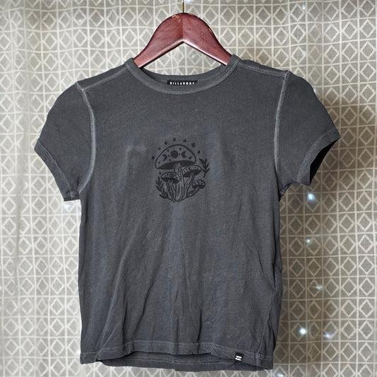 Gray t-shirt with a mushroom print on a hanger against a patterned wall