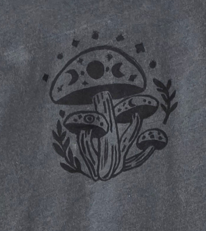 Gray t-shirt with a logo on a hanger against a patterned wall