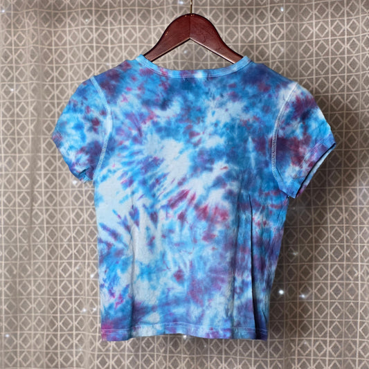 Tie-dye t-shirt on a hanger against a patterned wall