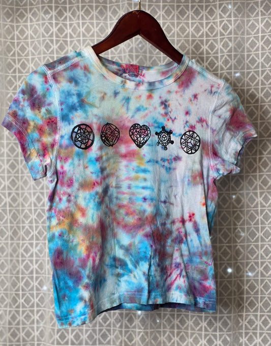 Tie-dye t-shirt with heart and star designs on a hanger against a patterned wall.