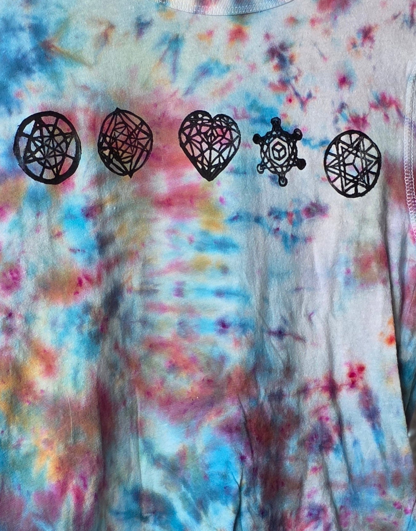Tie-dye shirt with black symbol designs on a colorful background