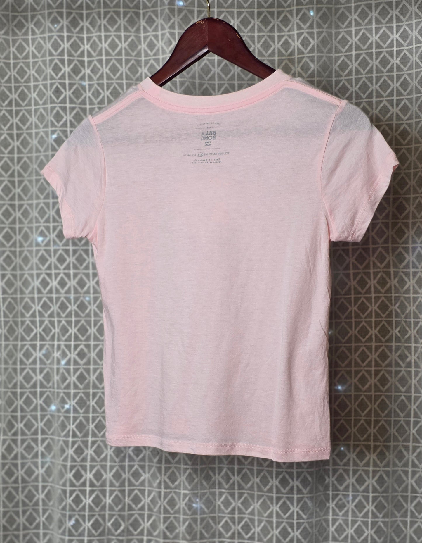 Pink t-shirt on a hanger against a patterned wall