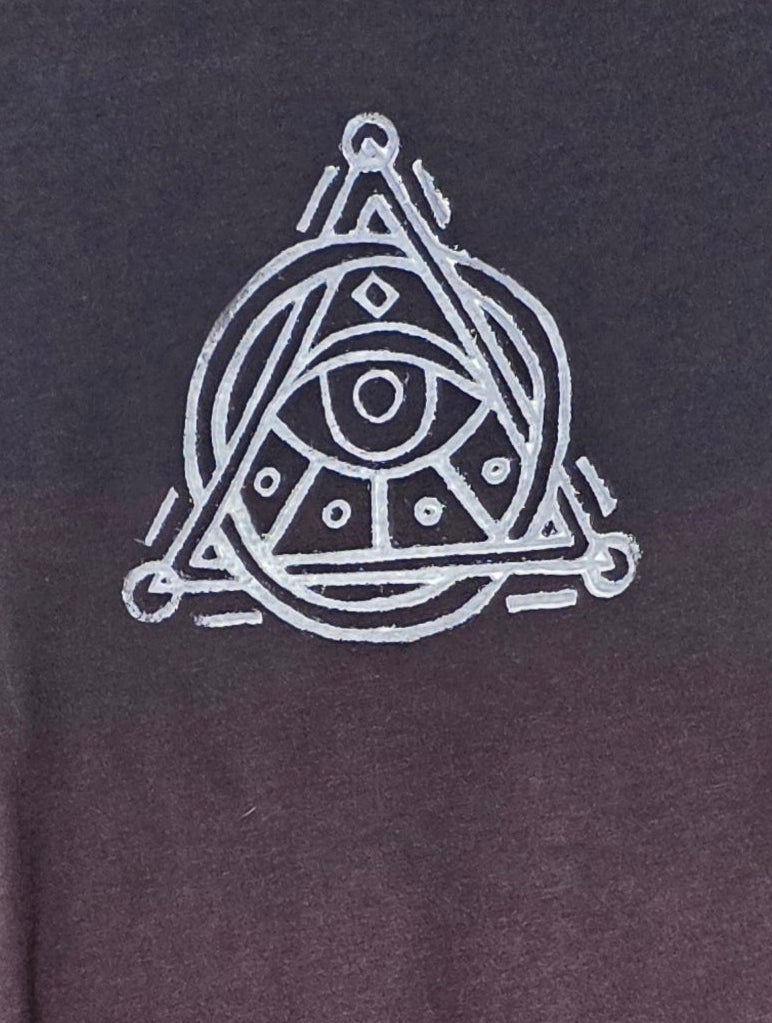 Black t-shirt with a white triangle symbol on a hanger against a patterned wall.