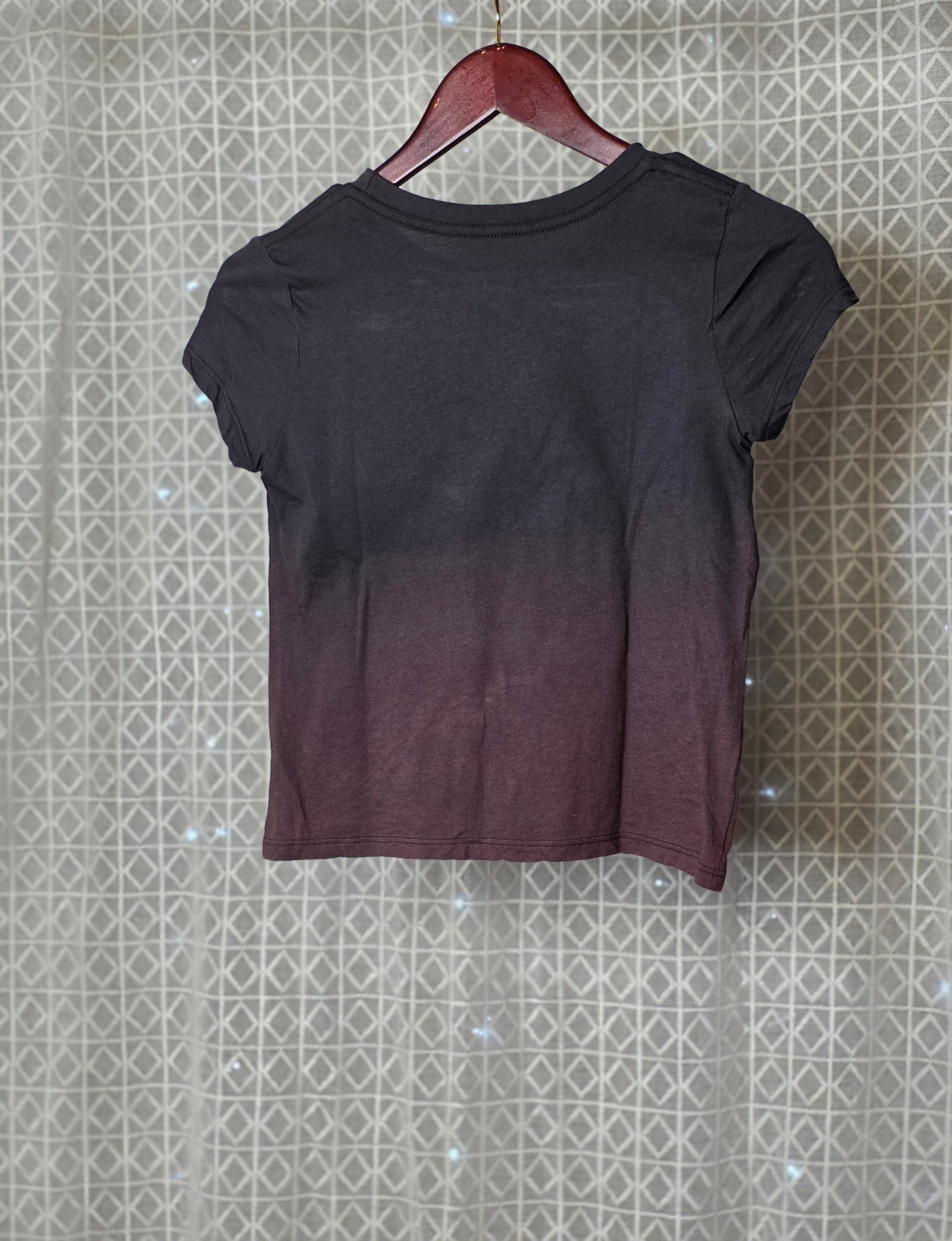 Black t-shirt on a hanger against a patterned wall