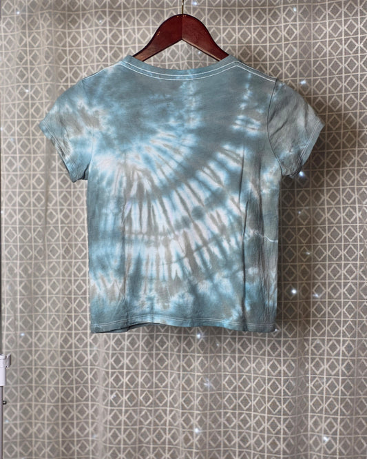 Tie-dye t-shirt on a hanger against a patterned wall