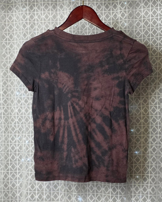 Tie-dye t-shirt on a hanger against a patterned wall