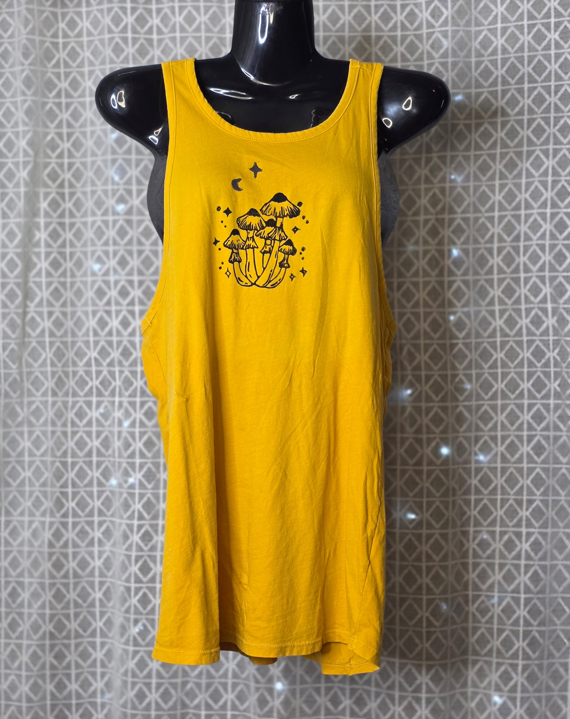 Yellow tank top with black graphic design on a mannequin against a patterned wall.