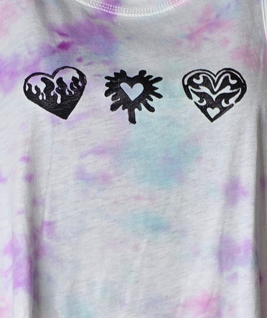 Tie-dye tank top with heart designs on a mannequin against a patterned background