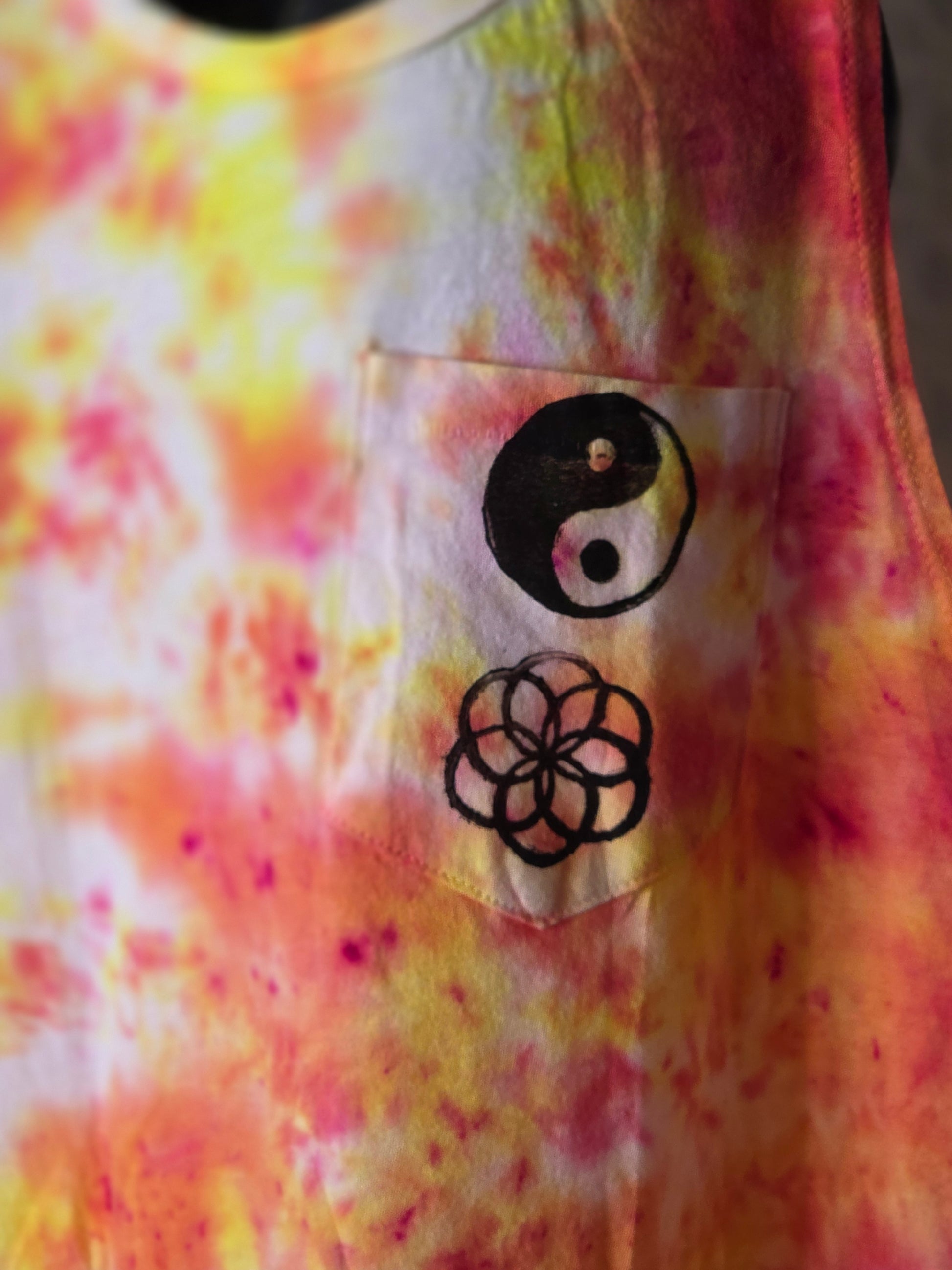Colorful tie-dye fabric with a black and white symbol and a black floral design on a clear label.