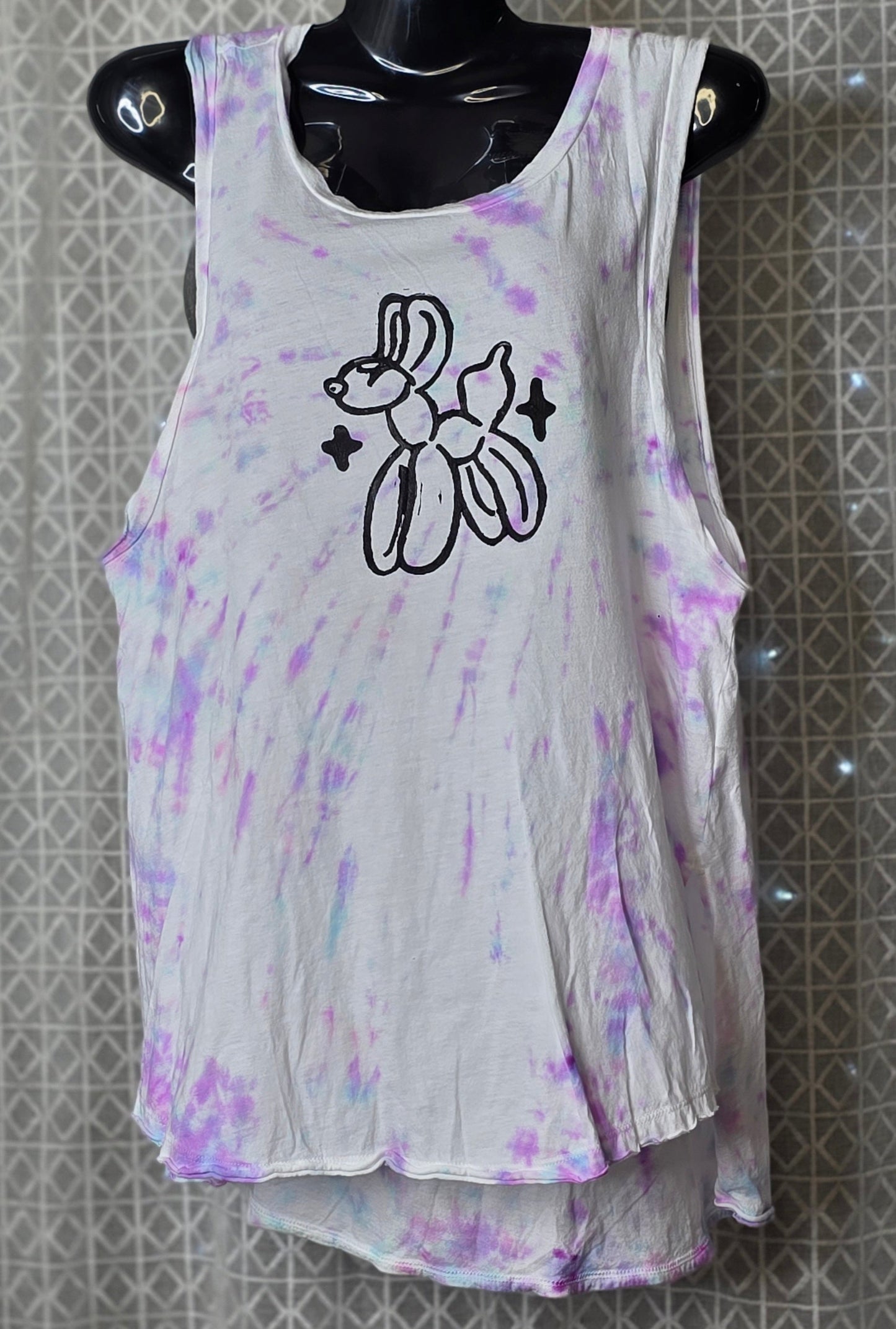 Tie-dye tank top with a  balloon animal graphic design on a mannequin against a patterned wall.
