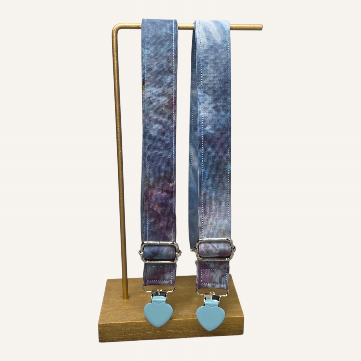Suspenders with blue tie on a gold stand against a white background