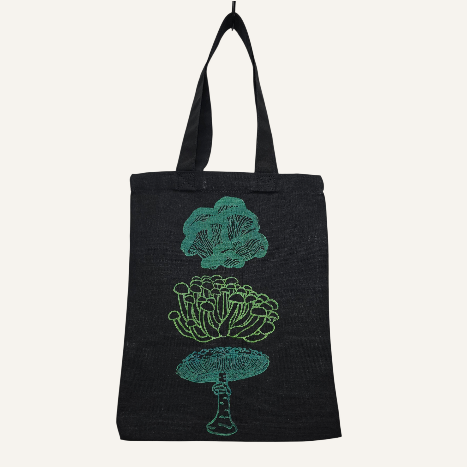 Black tote bag with teal mushroom illustrations on a white background