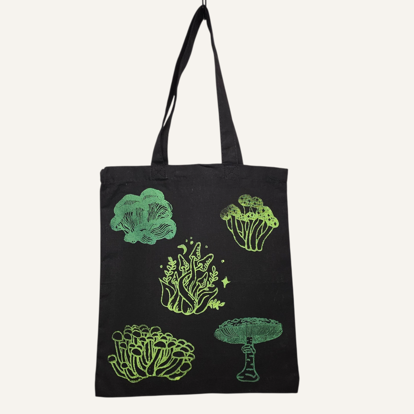 Black tote bag with green mushroom designs on a white background