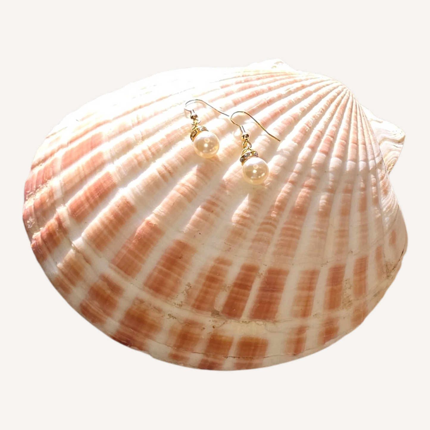 Shell with pearl earrings on a white background