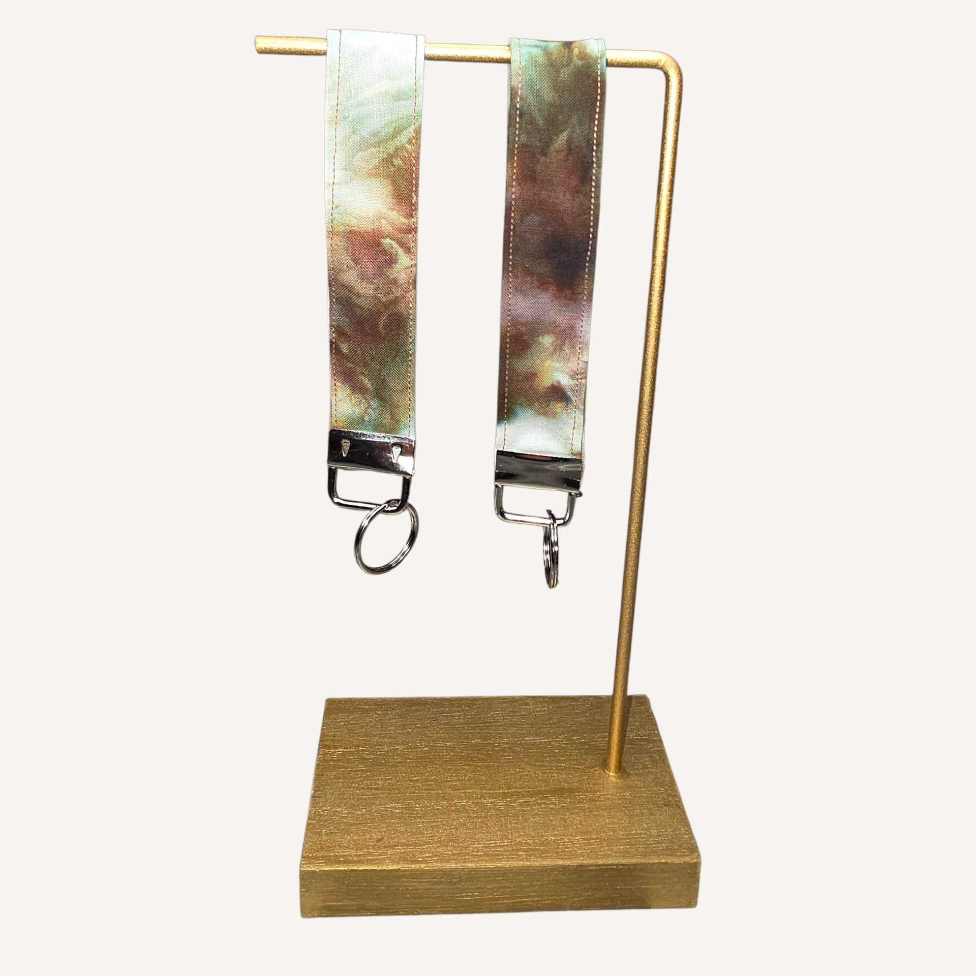 Two colorful lanyards on a gold stand against a white background