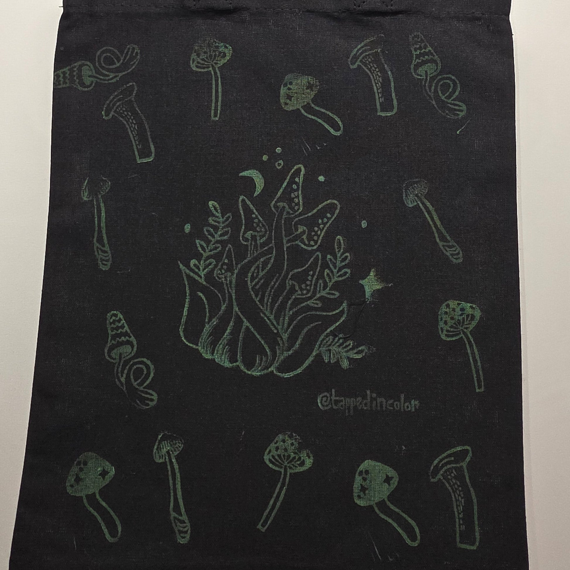 Black tote bag with green illustrations on a white background