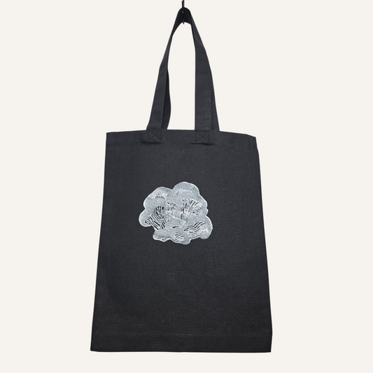 Black tote bag with a white oyster mushroom design on a light gray background